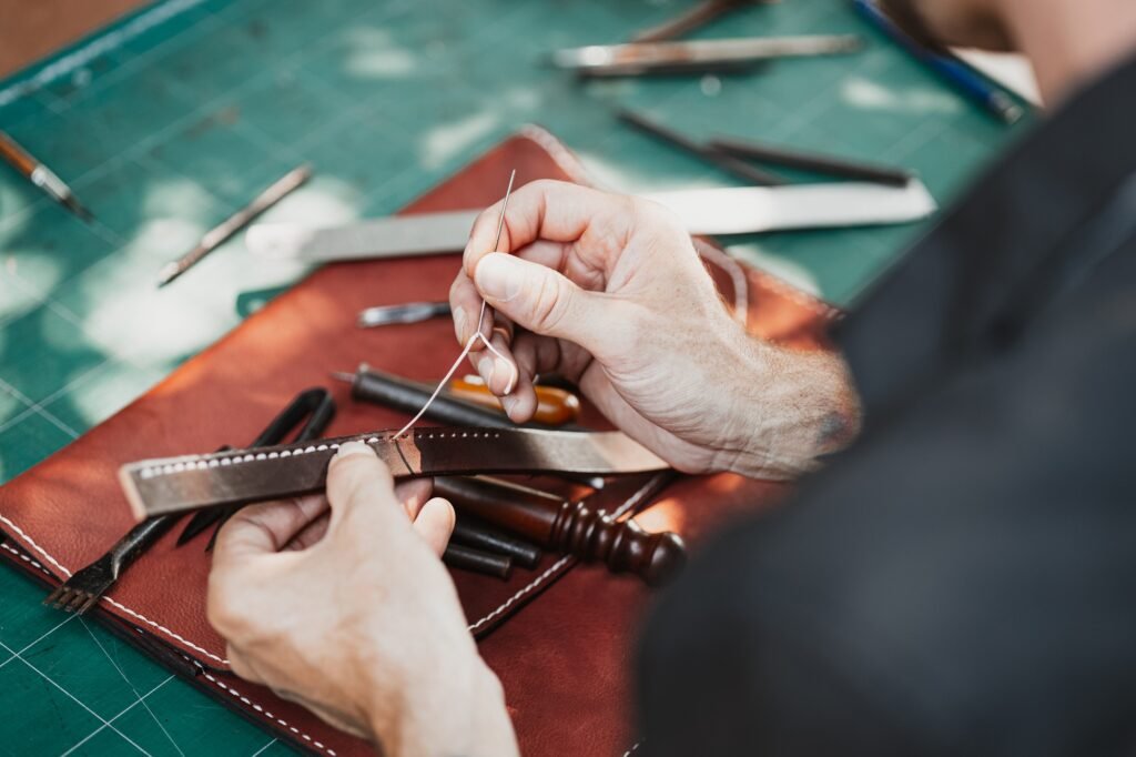 leather handcraft in the leather workshop sewing to make a wallet. Tanner in old tannery.
