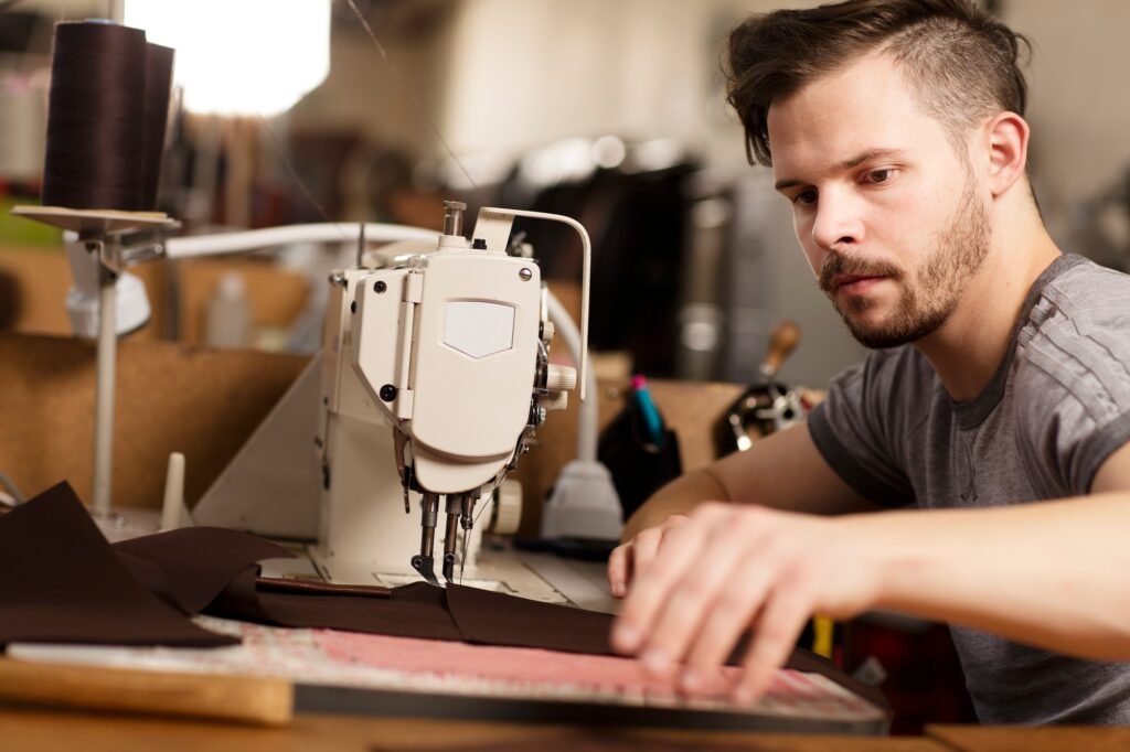 Man using sewing machine to sew leather in leather jacket manufacturers