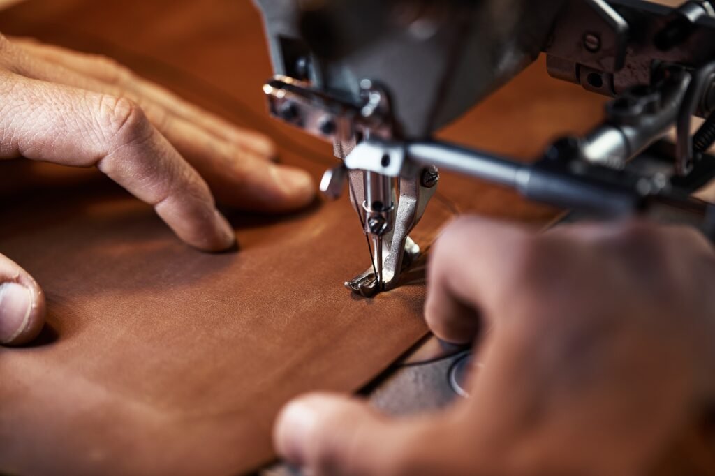 Working process of leather craftsman. Tanner or skinner sews leather on a special sewing machine