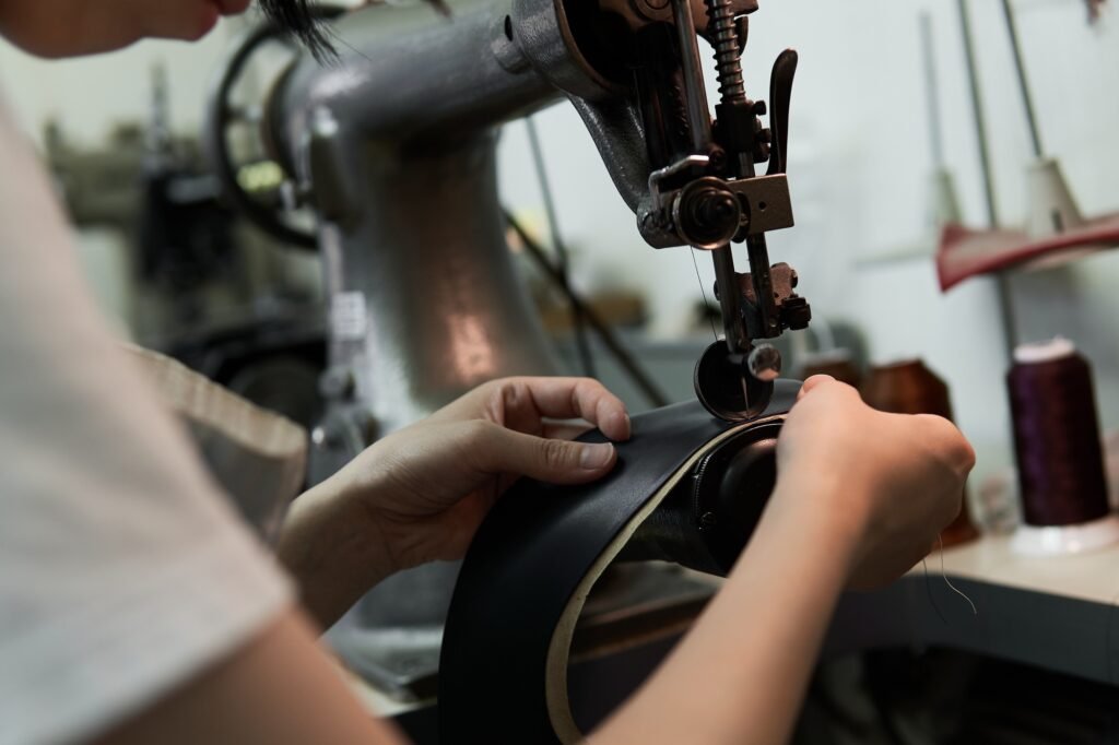 A woman's hand sewing leather with a sewing machine