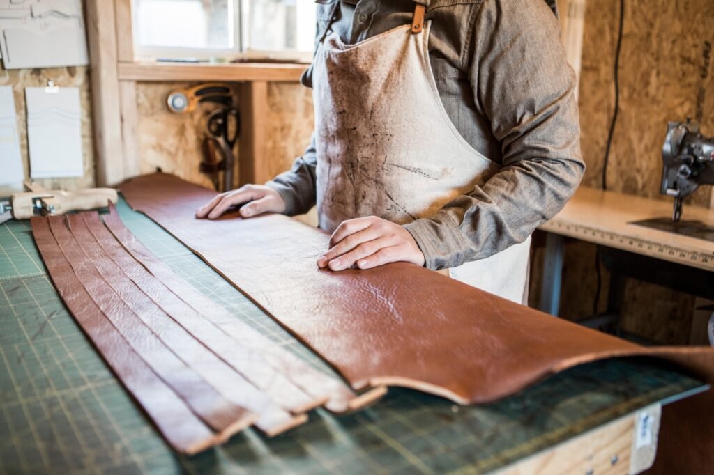 Leather craftsman with strips of leather on workshop bench